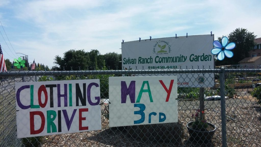 A sign invites passers-by to participate in a clothing drive for the community garden.