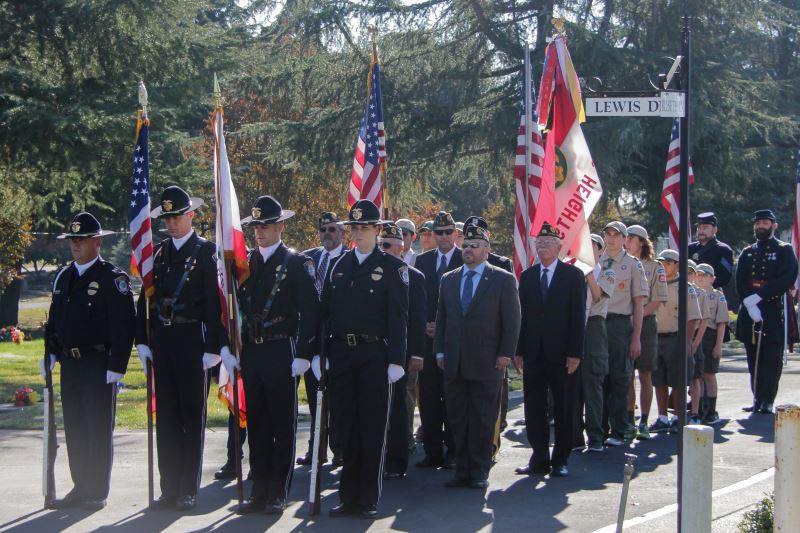 A four-member police "Color Guard" leads a march around the "Avenue of Flags" at Sylvan Cemetery, during a 2015 Veterans Day event. // Photo, Dorina Choban