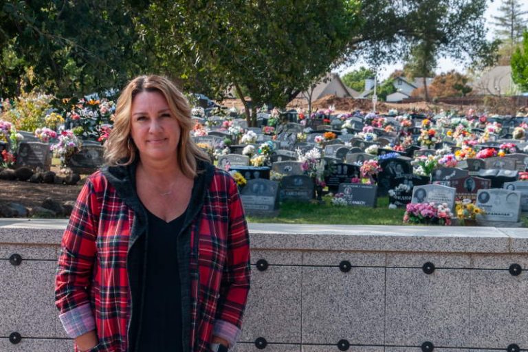 General Manager Cyndi Price stands with grave sites in the background at Sylvan Cemetery. // M. Hazlip