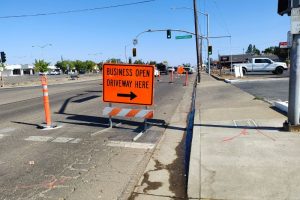 Temporary Bright orange sign that reads "Business Open. Driveway Here."