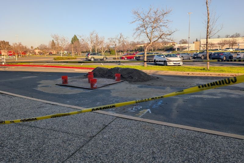 A portion of roadway is blocked off with caution tape and construction cones behind the Sunrise Mall food court 