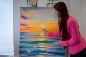 Local Ukrainian artist Veronika Buliuk paints an ocean sunset scene. // Mike Hazlip