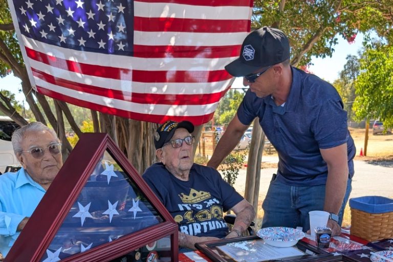 WWII veteran Emil Giusti (middle) sits with longtime friend and coworker, (left) as his grandson speaks to him (right) during his 100th birthday party. // SB Williams