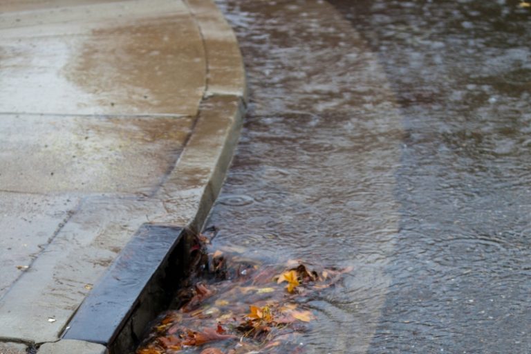 Rain water running into a storm drain for collection. Stock photo