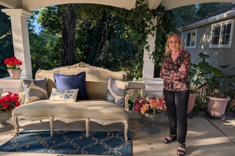 Award-winning photographer Diane Miller stands in her home studio beneath a covered balcony walkway. // SB Williams